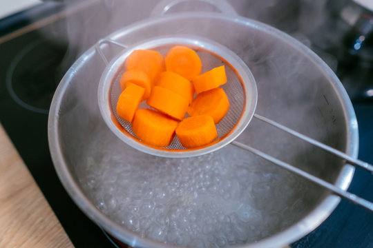The image of a small amount of chopped carrots over a boiling pan