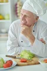 Portrait of elderly male chef cooking at kitchen