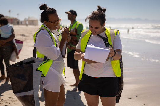 Volunteers discussing over clipboard on the beach