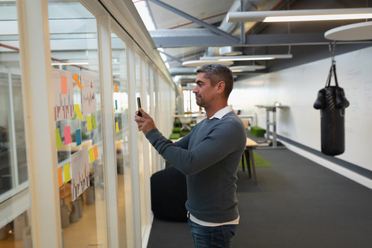 Businessman capturing photos  of stick notes in office