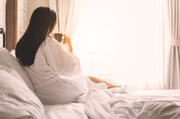 asian woman relaxing in the hotel room, drinking morning coffee, copy space