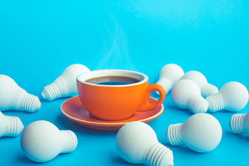 Idea and creativity concepts with hot coffee cup and light bulb on blue background