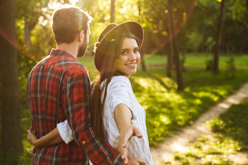 Positive young loving couple walking outdoors in a green nature park forest.