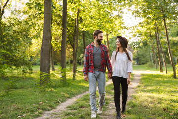 Fototapeta premium Smiling positive young loving couple walking outdoors in a green nature park forest.