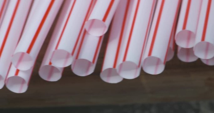Close up pan across a row of red and white plastic soda straws