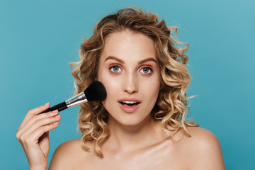 Image of beautiful half-naked woman applying makeup with powder brush