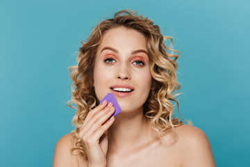 Image of pretty half-naked woman applying makeup with sponge