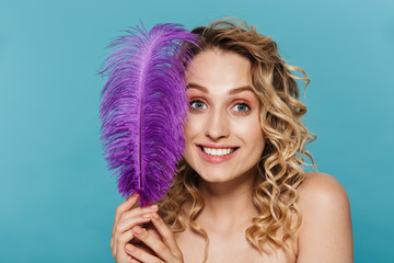 Image of happy half-naked woman with curly hair smiling while holding soft feather