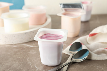 Composition with plastic cups with yogurt on grey table, space for text