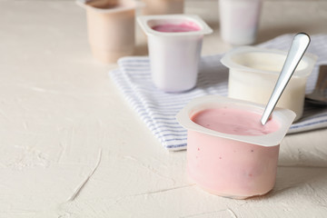 Composition with plastic cups with yogurt on white table
