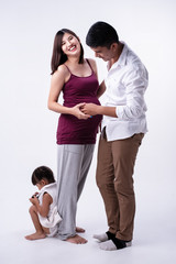 The pregnant woman standing beside husband,her daughter sitting on ground floor at the left side,Happy family,Love and care feeling