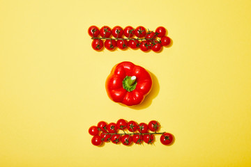 flat lay with red cherry tomatoes and paprika on yellow background