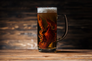 red lobster in glass with beer on wooden surface
