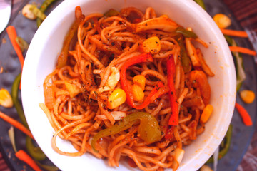 Veg noodles in a bowl topped with capsicum,sweet corn and herbs