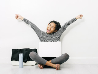 Happy Asian girl using laptop and raising hands with fabric handbag and water bottle, lifestyle concept.