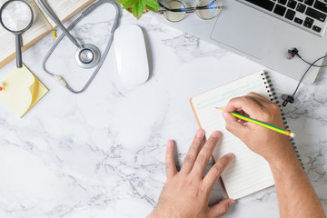 Doctor writing blank notebook on marble table