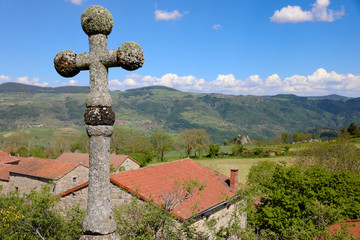 Croix de pierre au dessus d'un village. Paysage de campagne vallonnée l'été en Auvergne. Nature,...