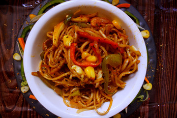 Veg noodles in a bowl topped with capsicum,sweet corn and herbs