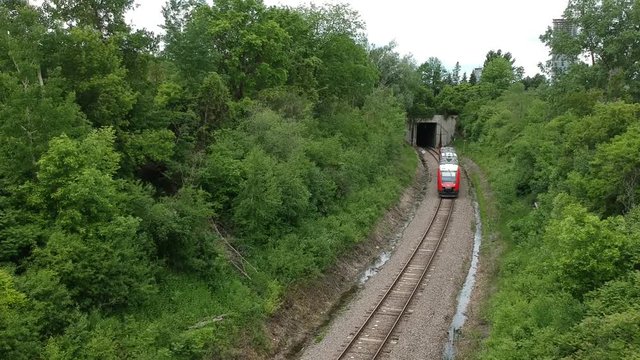 O-Train coming down the track in Carelton University and drone flying over top of train on tracks.