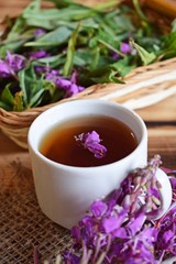 Traditional Russian herbal drink. Ivan-tea in a Cup close-up on a wooden table. It has a positive...