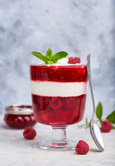 Layered dessert in glass with raspberries, jelly, yogurt and jam