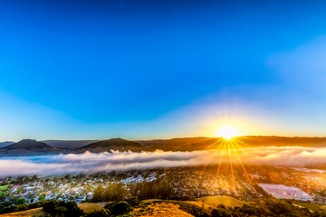 Sunburst above Clouds and Mountains, City