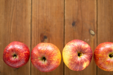 fruits, food and harvest concept - ripe red apples on wooden table