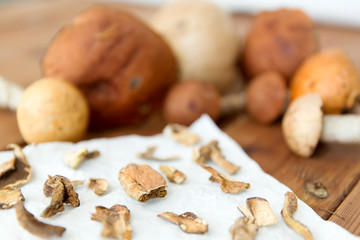 culinary, food and cooking concept - dried mushrooms on baking paper on wooden background