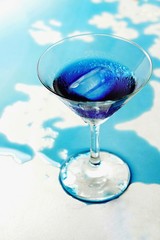 Fresh purple butterfly pea or blue pea flower and juice in glass on  table blue and white background with green blur light space background design, photo montage or advertising