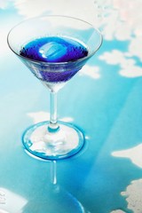 Fresh purple butterfly pea or blue pea flower and juice in glass on  table blue and white background with green blur light space background design, photo montage or advertising