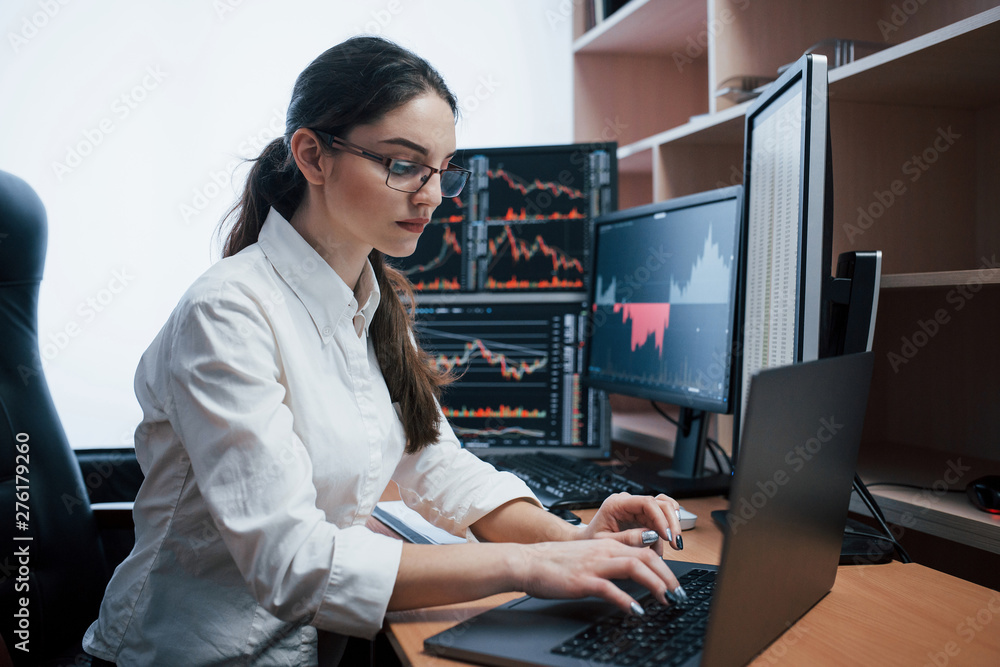 Poster typing on the laptop. woman working online in the office with multiple computer screens in index cha