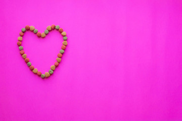 Creative valentines concept photo of Dog food and a heart be lovely on pink background.