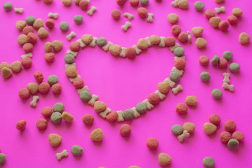Creative valentines concept photo of Dog food and a heart be lovely on pink background.