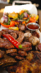 Mixed grilled meat platter. Assorted delicious grilled meat with vegetable. Mixed grilled meat with pepper sauce and vegetables.