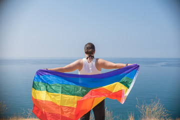 Young girl from behind, holding a banner looking at the sea