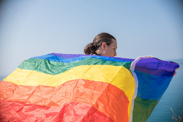 Young girl from behind, holding a banner looking at the sea