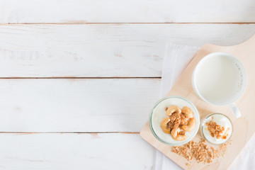 Healthy meal made of granola in glass, Yogurt and cornflakes Decorate food with Cashew Nut with hot milk setting on white wooden table, healthy care concept, copy space
