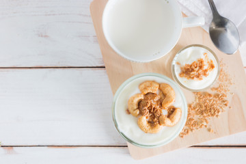Healthy meal made of granola in glass, Yogurt and cornflakes Decorate food with Cashew Nut with hot milk setting on white wooden table, healthy care concept, copy space