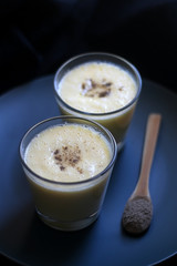 Two glasses of refreshing mango lassi drink, decorated with cardamom. Dark background, selective focus.