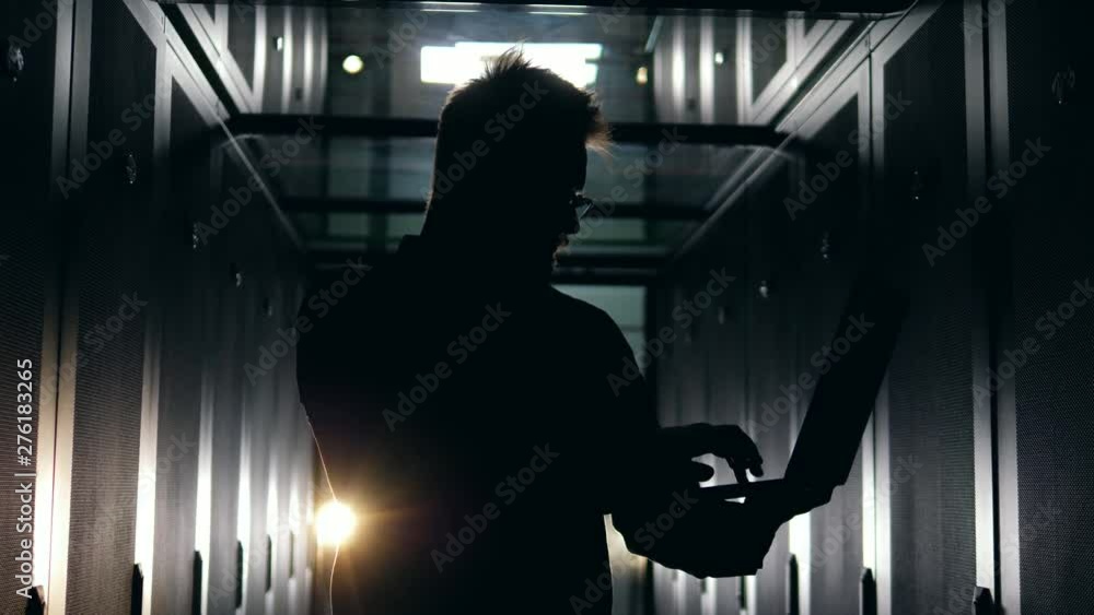 Poster a man works at a data center, typing on a laptop. server technician working in modern data center.