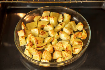 Delicious baked potatoes on glass plate, black background
