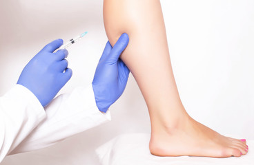 Doctor cosmetologist makes rejuvenation beauty injection to the calf muscle on the leg of the girl. Rejuvenation with injections of Hilauri acid, medical