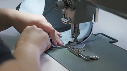 needle of the sewing machine in motion, close-up. needle of sewing machine quickly moves up and down. process of sewing leather goods. Tailor sews black leather in sewing workshop.