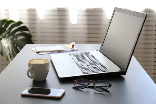 Office interior design concept. White laptopp with black keyboard, desk w/ matte blue table top. Computer, blank skreen smartphone. Freelance blogger writing an article. Close up, copy space for text.