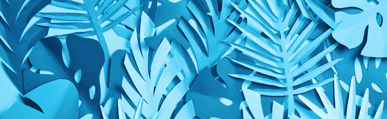 seamless pattern of blue exotic paper cut palm leaves on blue background with copy space, panoramic shot