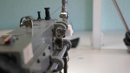 Tailor sews black leather in sewing workshop. needle of sewing machine in motion. process of sewing leather goods. two needles of the sewing machine quickly moves up and down, close-up.