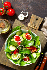 Vitamin snack. Salad with fresh vegetables and spinach on a dark stone or concrete table. Free space for your text.
