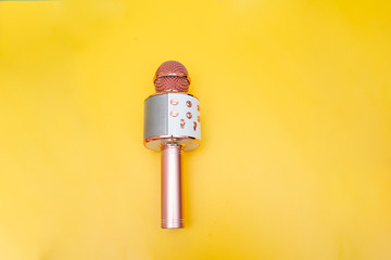 Pink-silver portable karaoke microphone for children on a bright yellow background