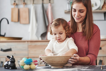 Proud woman smiling. Mother teaches daughter to paint the eggs for the Easter holidays