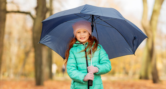 childhood, season and people concept - happy little girl with umbrella at autumn park